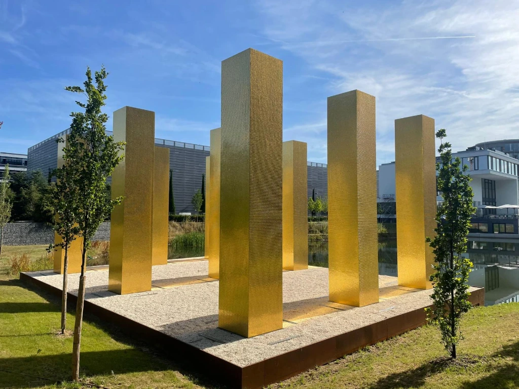 Goldene Säulen auf einem Kies-Plateau vor der 1+1 Kantine in Montabaur 